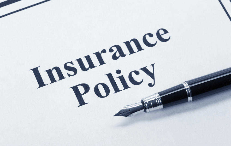 Photo of an insurance policy contract and pen atop a desk