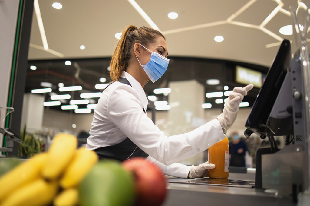 Photo shows a cashier with a face mask entering an order on to a cash register