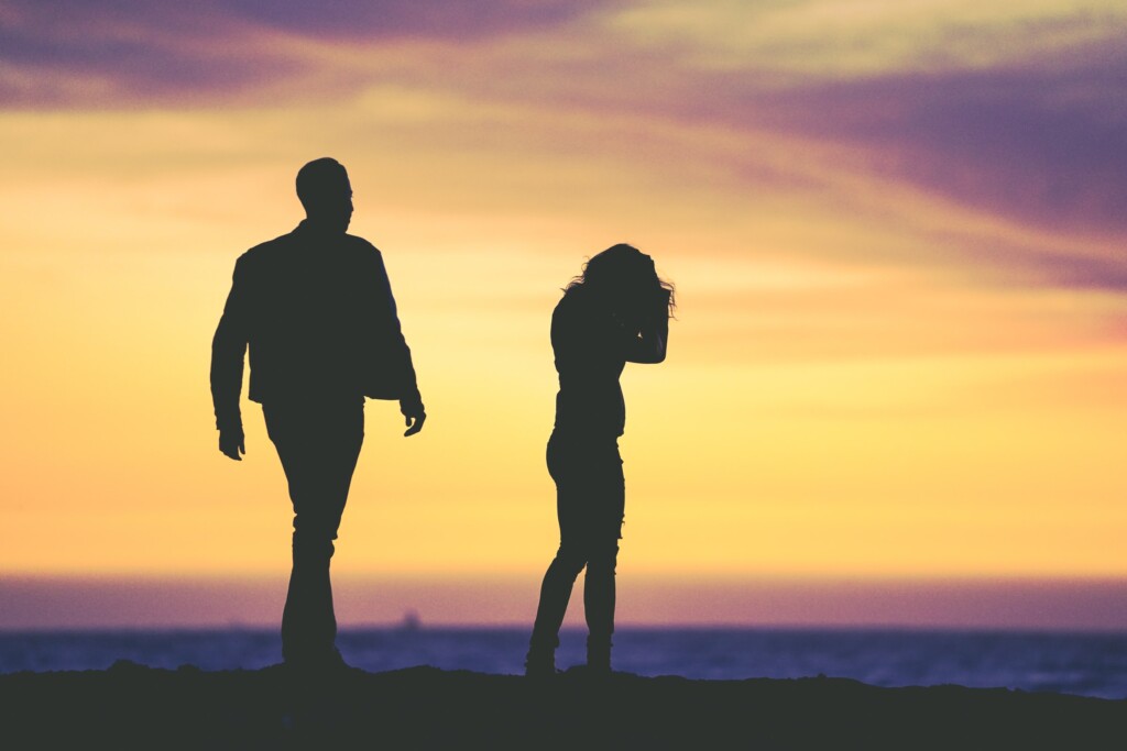 Silhouette of a couple walking away from each other at sunset